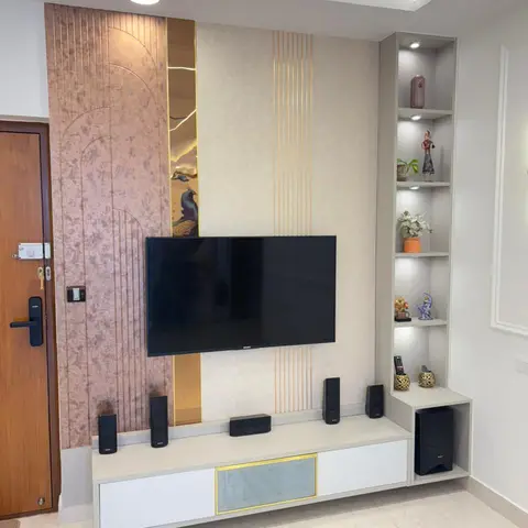 A living room TV wall with mauve textured wallpaper accented by a brass peacock-motif inlay strip, a white floating TV console