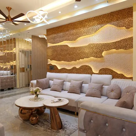 A living room with a backlit textured copper-and-gold accent wall behind a tufted grey velvet sofa with gold trim