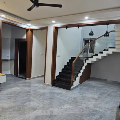 A living room with a book-matched marble TV wall and backlit floating console, opening onto a staircase lit by a row of black glass pendant lights.