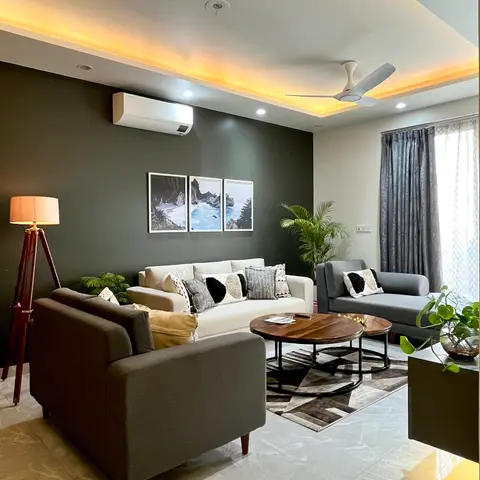A living room with a charcoal accent wall, cove-lit ceiling, and a mix of cream and grey sofas around nested round coffee tables.