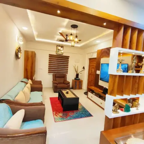 A living room with a coffered false ceiling and cluster pendant lights, teal-cushioned sofas around a red-patterned rug