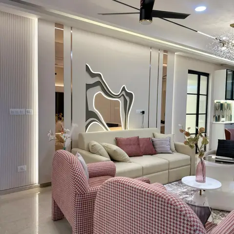 A living room with a cream sofa and houndstooth armchairs in mauve tones beneath a sculptural backlit mirror wall feature and fluted panelling.