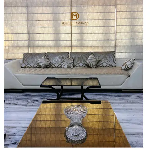 A living room with a cream sofa and patterned throw pillows against a backlit patterned roman blind
