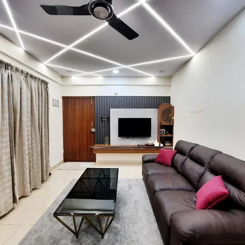 A living room with a criss-cross linear-lit false ceiling, grey fluted panelling behind a marble-backed floating TV unit
