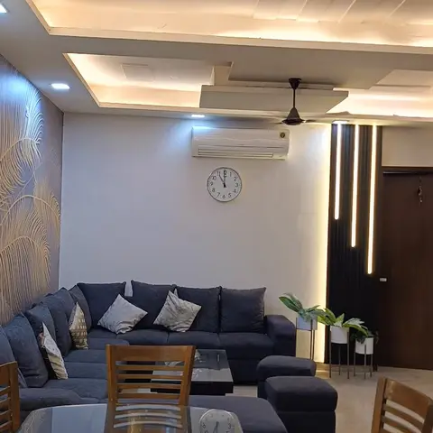 A living room with a feather-motif textured accent wall flanked by vertical LED light strips, a multi-tier cove ceiling