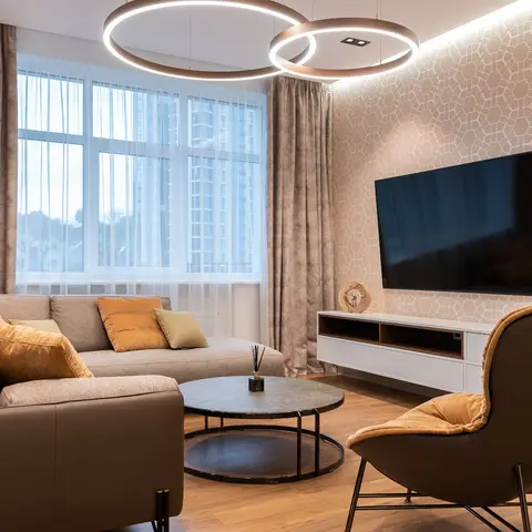 A living room with a geometric-patterned accent wall behind a floating TV console, twin ring pendant lights