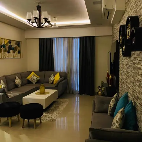 A living room with a grey sectional sofa in yellow and floral cushions facing a white coffee table