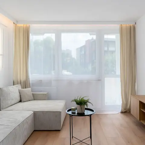 A living room with a light grey corduroy L-shaped sectional sofa, a round black side table
