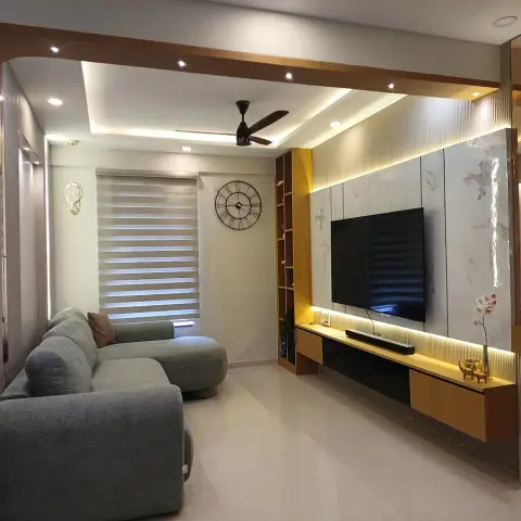 A living room with a marble-slab TV wall edged in backlit reveals over a wall-hung oak console, a slim open-shelf column beside it