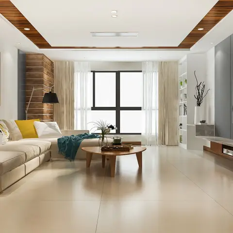 A living room with a mustard-and-teal-cushioned sectional sofa, a round wood coffee table, and a grey-panelled TV wall with a marble-topped console
