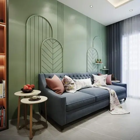 A living room with a sage-green feature wall detailed in arched chevron moulding, a blue-grey tufted sofa with floral throw pillows
