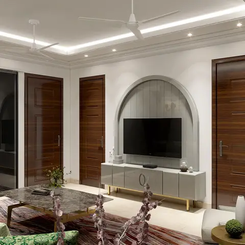 A living room with an arched grey fluted TV niche flanked by walnut panelled doors, cove-lit ceiling, and a marble-top coffee table on brass legs.
