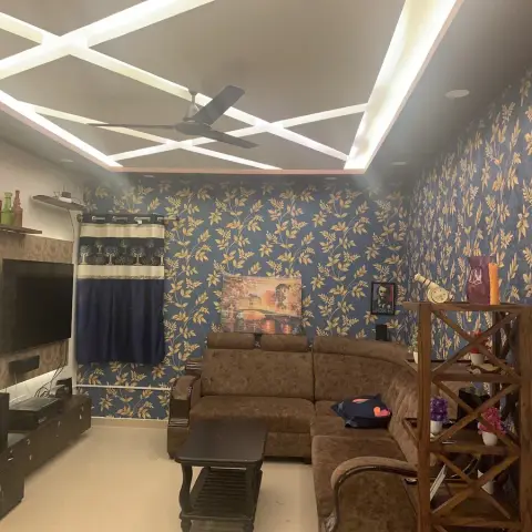 A living room with dark blue leafy-print wallpaper, a criss-cross geometric LED cove ceiling