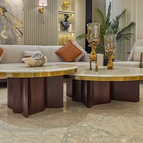 A living room with two round brass-rimmed marble coffee tables on nested wood plinths
