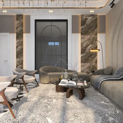 A luxury living room with a brass-trimmed marble panel wall, a curved grey sofa and sculptural wood coffee table