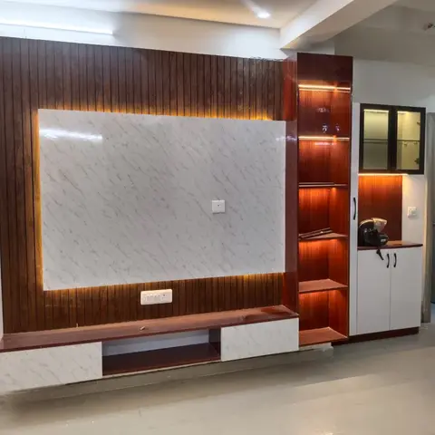 A mahogany wood-panelled TV wall unit with a backlit marble-clad centre panel and a lit open-shelf display column beside a white cabinet.