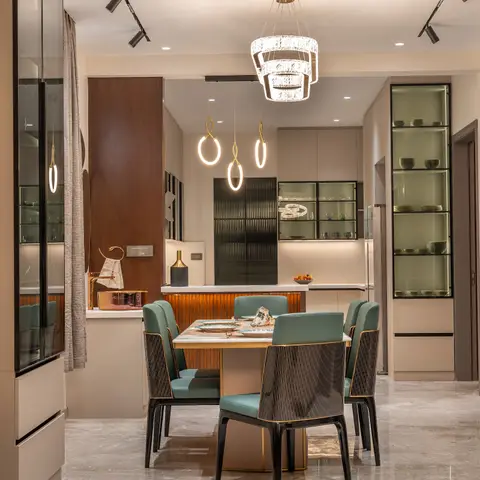 A marble-top dining table with teal leather and black fluted chairs sits beneath a tiered crystal chandelier and trio of ring pendants