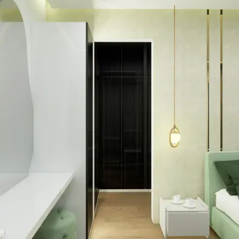 A mint-green upholstered bed with a dark green cushion and a white cube bedside carrying two tea cups
