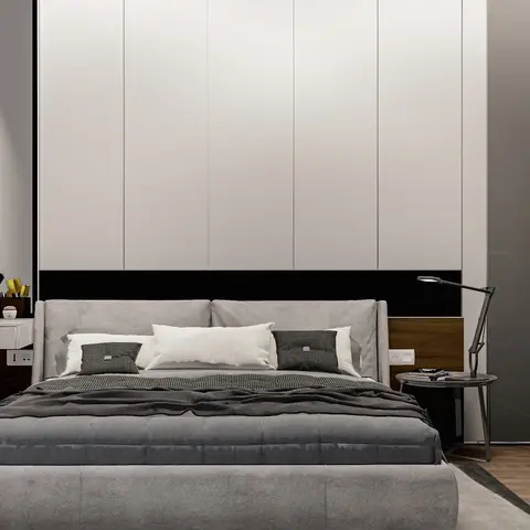 A modern bedroom with a grey upholstered bed against a full-height white panel headboard wall, a floating dressing table styled with makeup accessories