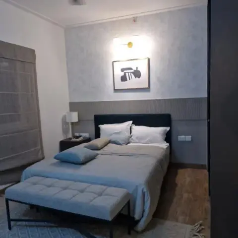 A navy upholstered headboard against mottled grey wallpaper with a grey fluted dado band at pillow height