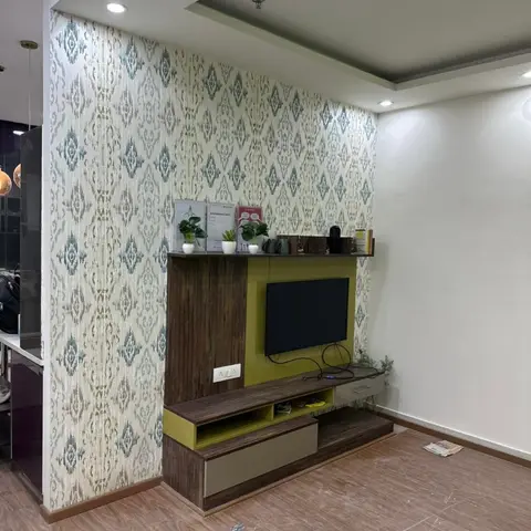A newly finished living room with an ikat-print wallpaper feature wall behind a walnut-and-olive-green TV unit