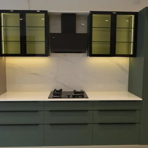 A newly installed straight-line kitchen in olive matt shutters with black inset pulls, flanked by black-framed glass wall cabinets lit from within