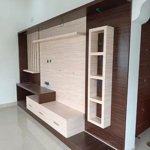 A newly installed TV unit wall with a dark wood-grain frame surrounding a light wood-grain panel and a vertical stack of open display niches