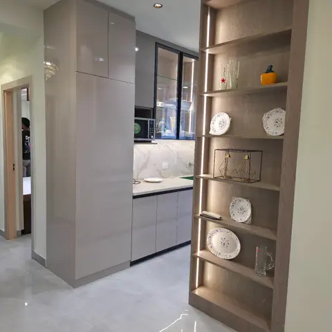 A passage view into a kitchen with glossy grey tall units and a white marble-look backsplash