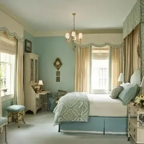 A pastel seafoam-and-cream traditional bedroom with an elaborate valance curtain treatment, a chandelier and a matching quilted bedspread.