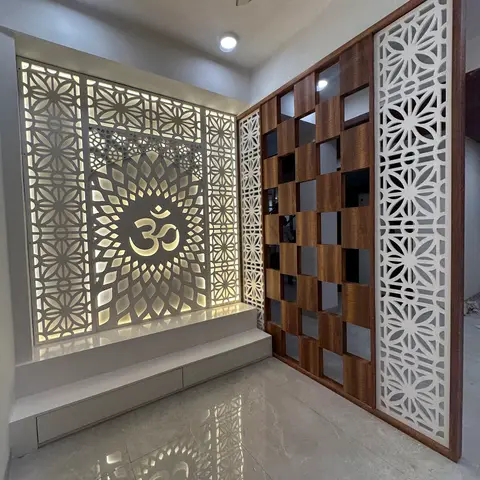 A pooja alcove with a large backlit CNC jaali panel featuring an Om motif, beside a wood-and-jaali checkerboard partition screen.