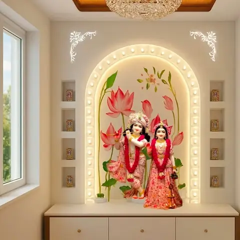 A pooja room with a backlit arched niche housing Radha Krishna idols against a painted lotus mural, flanked by display niches above a floating cabinet.