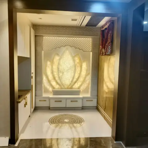 A pooja room with a backlit carved-onyx lotus-petal feature wall framed by a jaali lattice screen and swastika border