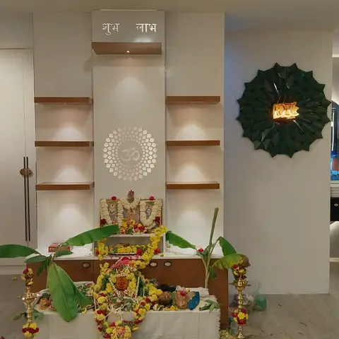 A pooja unit mid-ceremony with elaborate marigold garlands and banana leaves draped over it