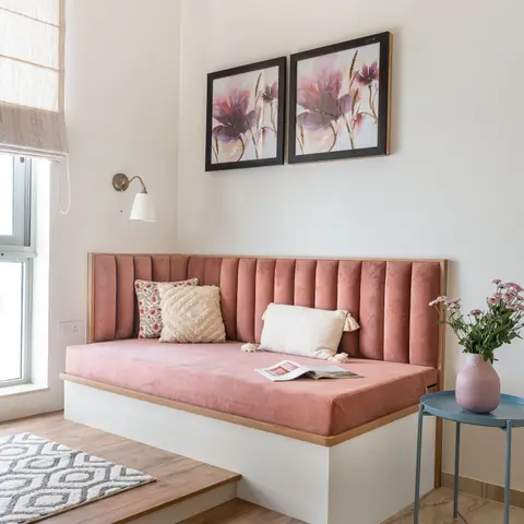 A raised platform daybed with blush-pink channel-tufted velvet upholstery, a pair of matching floral wall art prints