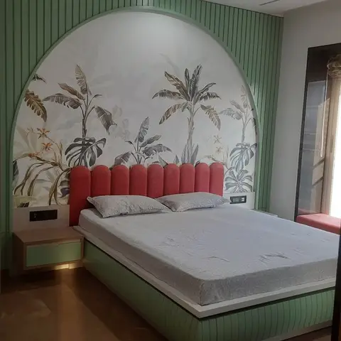 A real photo, bedroom with a fluted-green arch wall framed around a tropical banana-leaf mural, a coral scalloped upholstered headboard