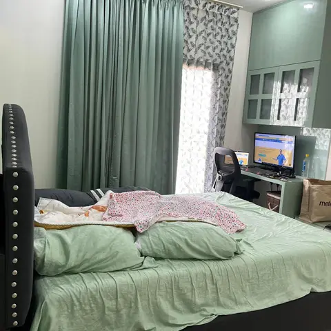 A real photo, lived-in bedroom with a black tufted bed, sage-green bedding and curtains