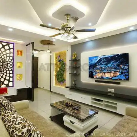 A render of a living room with a multi-layer cove-lit POP ceiling, a backlit Om mandala jaali wall panel beside illuminated display niches