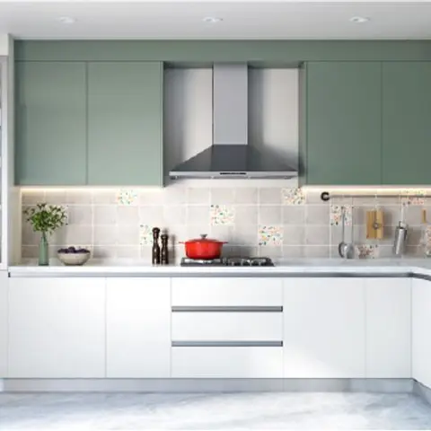 A sage-green and white modular kitchen with a patterned tile backsplash, a stainless steel chimney hood, and a glass-fronted display unit beside the counter.