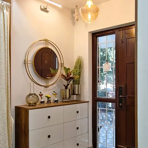 A six-drawer white gloss shoe console framed in walnut on brass-tipped legs, topped with brass planters and small figurines