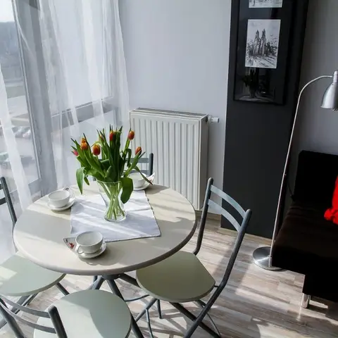 A small round dining nook with pastel bistro chairs and a marble-look table set with teacups and a vase of tulips