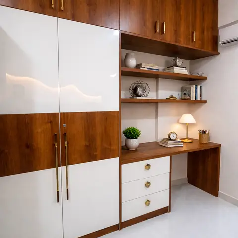 A study nook with a walnut-and-white gloss wardrobe with brass handles beside an open-shelf unit and a built-in study desk with white gloss drawers.