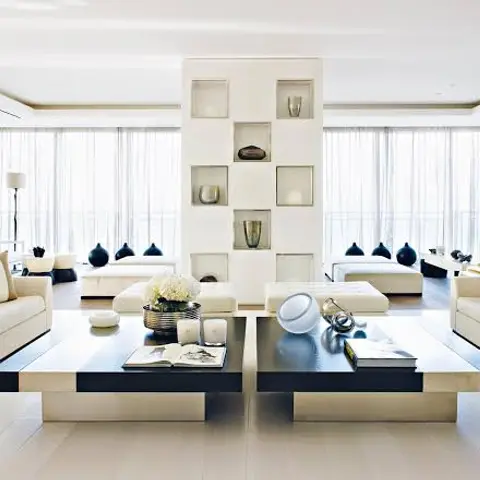 A symmetric cream living room with twin sofas facing dual black-and-cream coffee tables