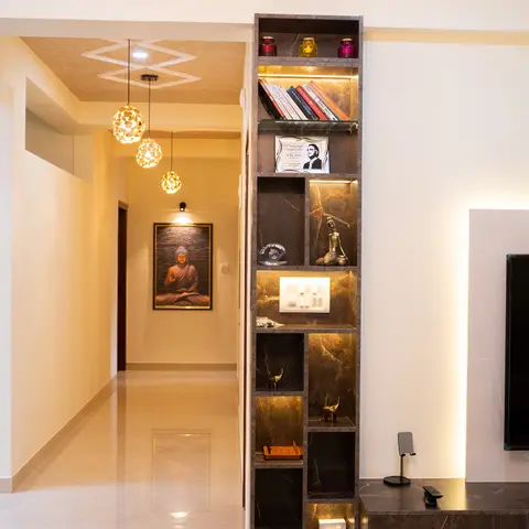 A tall backlit marble-effect display shelf styled with books and curios stands beside a floating TV console