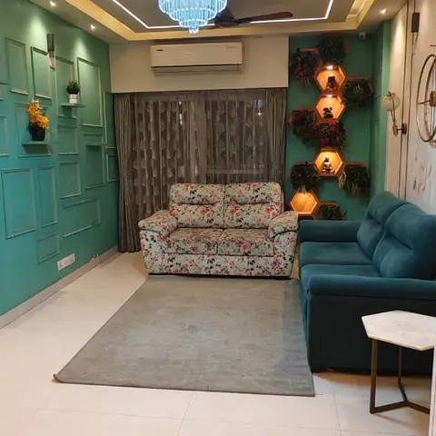 A teal wall panelled in raised squares holds backlit hexagonal plant niches beside a crystal chandelier