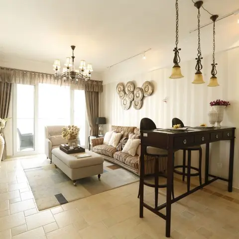 A traditional living room with a beaded-shade chandelier, a wall-mounted decorative plate display, and a striped sofa opening onto a curtained balcony.