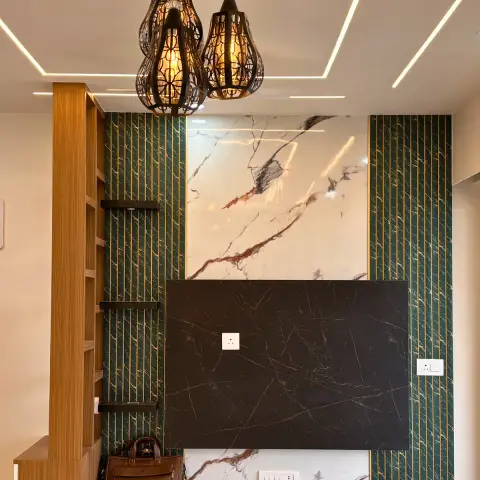 A TV feature wall combining book-matched marble cladding and green fluted gold-inlay panelling, lit by a cluster of dark metal lantern-style pendants.