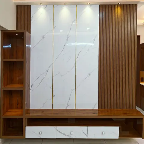 A TV feature wall with book-matched marble panels accented by brass inlay strips, flanked by fluted wood paneling and a floating wood-and-marble console.