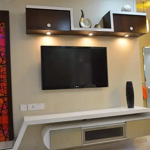 A TV unit wall with a floating white console, backlit overhead cabinets and a decorative orange stained-glass-style panel, adjoining an open bathroom.
