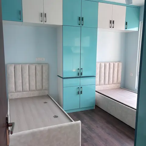 A twin-bed kids' room with a tall glossy teal-and-white wardrobe wall dividing two channel-tufted upholstered beds.
