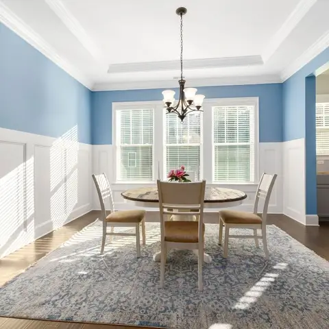 A two-tone blue-and-white dining room with wainscoting panel moulding, a tray ceiling